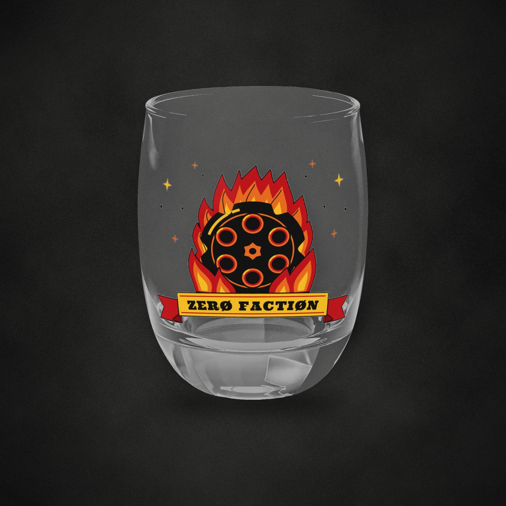 Zero Faction Six Shooter Inferno whiskey glass, front view of flaming revolver cylinder art, on dark asphalt backdrop