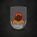 Zero Faction Six Shooter Inferno whiskey glass, front view of flaming revolver cylinder art, on dark asphalt backdrop